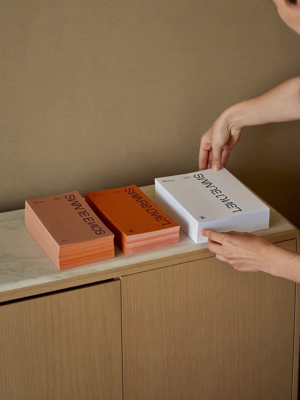 Three stacks of printed brand materials in distinct colour schemes side by side