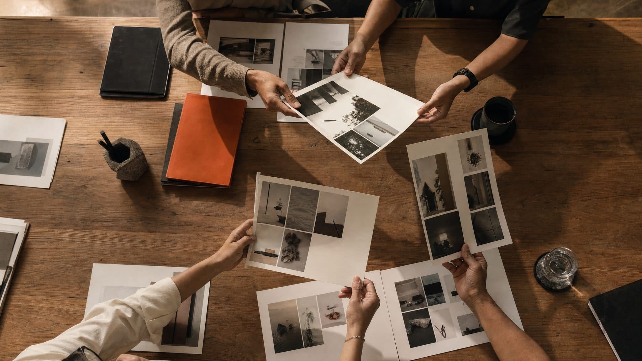 A team's hands passing printed campaign pages across a long table